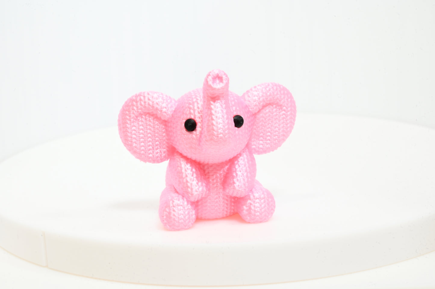 Super cute knitted style elephant with trunk in the air